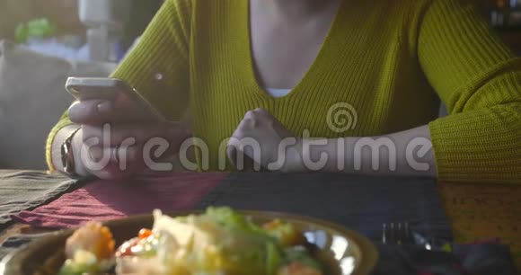 咖啡馆里的女人在等待时使用智能手机视频的预览图