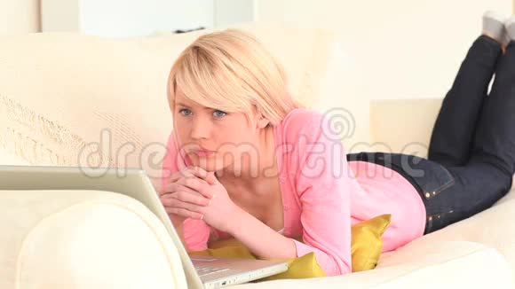 可爱的金发女人躺在沙发上视频的预览图