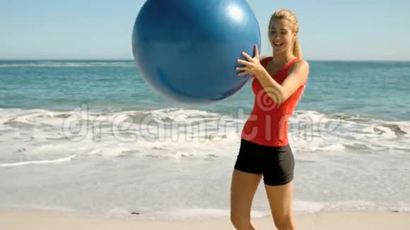 快乐的女人在海滩上玩她的健身球视频的预览图