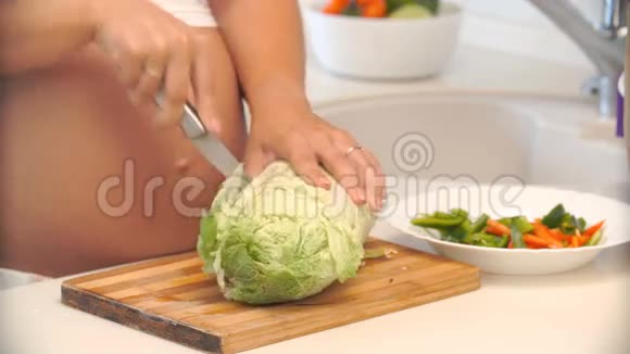 孕妇把卷心菜切在厨房的木板上视频的预览图