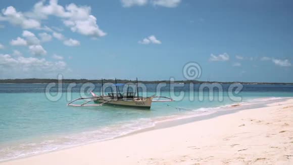 白色的班卡船在干净的绿松石水中锚定在白色的沙滩上视频的预览图