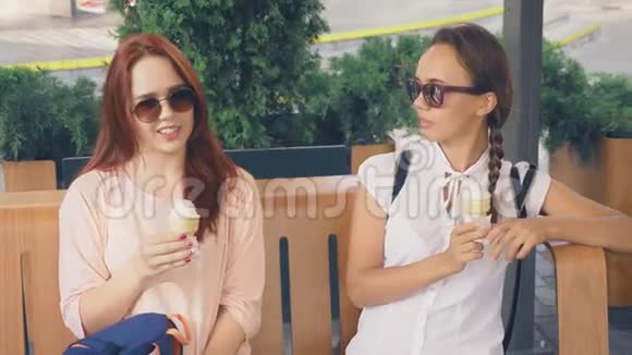 两个年轻的女人吃冰淇淋坐在户外咖啡馆里她们玩得很开心4K慢动作稳定视频的预览图