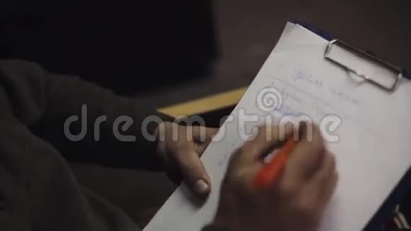 男人坐在椅子上用蓝笔在文件夹里的纸单上划下划线视频的预览图
