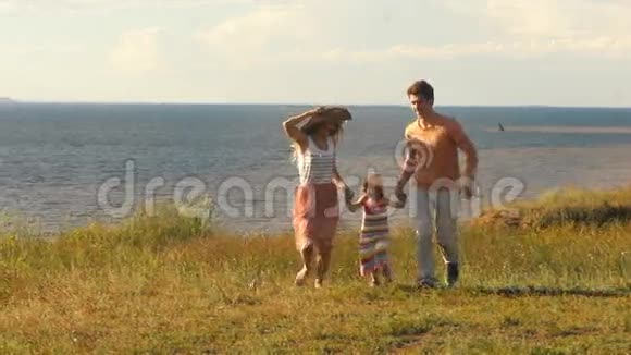 美丽的年轻家庭在河的背景和阳光下沿着悬崖奔跑视频的预览图