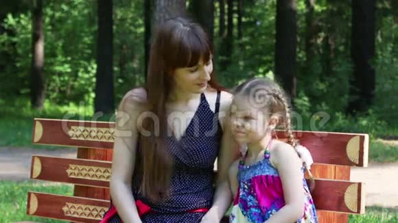 快乐的母女夏天坐在公园的长凳上视频的预览图