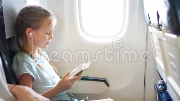 可爱的小女孩乘飞机旅行飞机窗户附近有笔记本电脑的可爱孩子视频的预览图