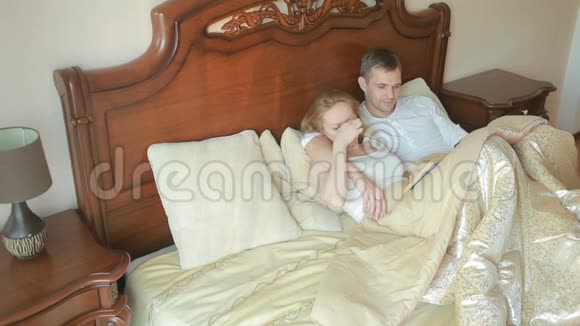 两个男人和女人躺在卧室的床上一起大声读这本书视频的预览图