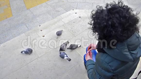 小镇广场上喂鸽子的女孩视频的预览图