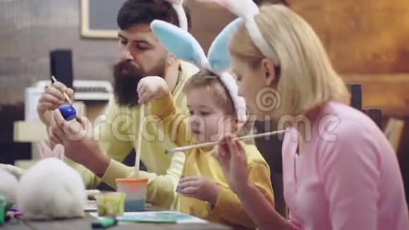 母亲父亲和儿子正在画鸡蛋幸福的家庭正在为复活节做准备复活节快乐可爱的小男孩视频的预览图