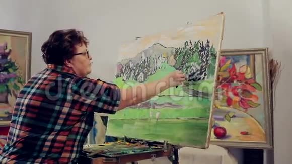 一个女人用调色板和画笔用油画颜料描绘风景视频的预览图