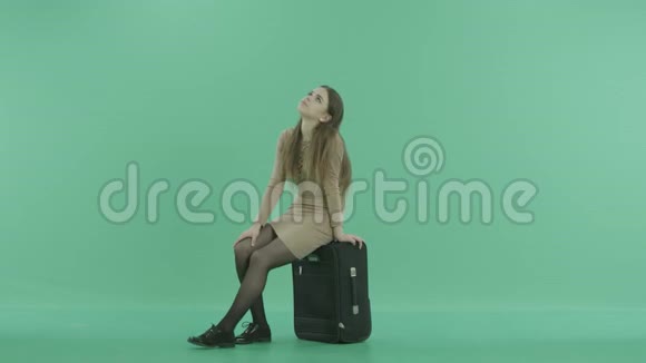 一个女孩坐在行李上等待视频的预览图