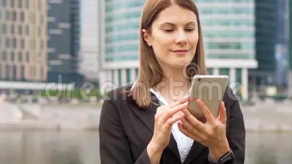 在市中心使用智能手机的女商人职业女性浏览聊天阅读新闻视频的预览图