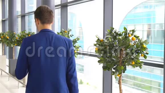 城市商人在机场里面穿西装外套的休闲小男孩在机场等候的白人男子视频的预览图