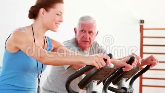 一位老人和他的教练一起使用健身自行车视频的预览图