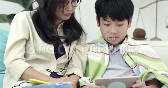 年轻的亚洲女人和年轻的男孩一起放松和听音乐视频的预览图