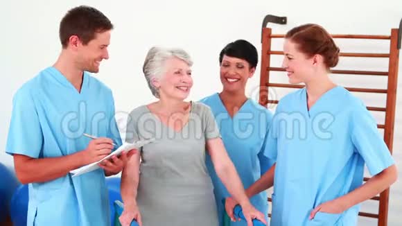 老年妇女微笑着与她的身体康复小组交谈视频的预览图