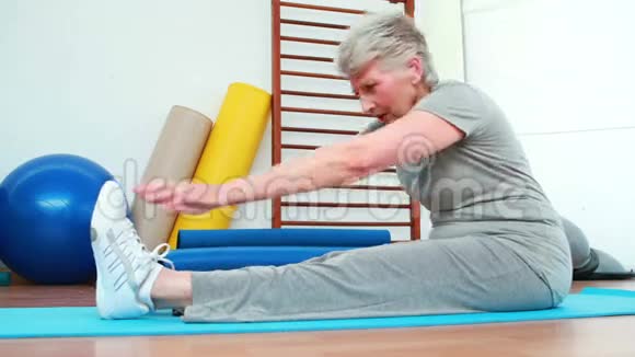 一位老年妇女在运动垫上触摸脚趾视频的预览图