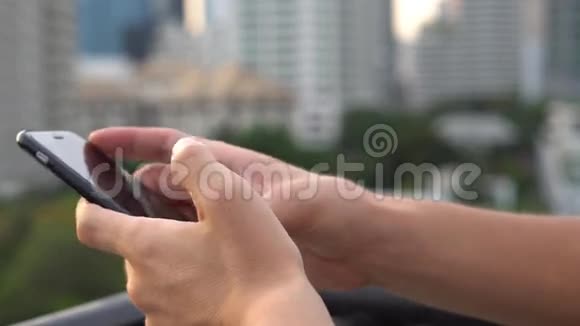 在大城市的屋顶上晚上使用手机浏览社交网络特写镜头4k视频的预览图