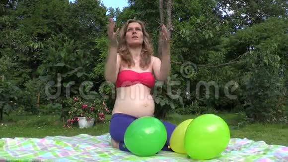 绿色公园里一个微笑的孕妇在玩彩色气球视频的预览图