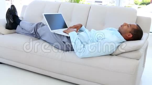 商人带着笔记本电脑在沙发上睡着了视频的预览图
