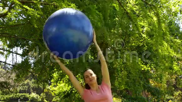 健身妇女在公园里举起运动球视频的预览图