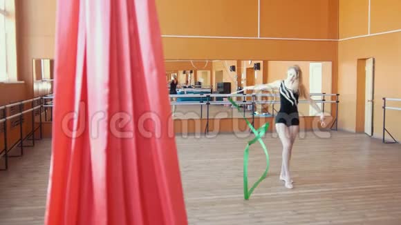 艺术体操年轻女子用绿色丝带训练体操视频的预览图