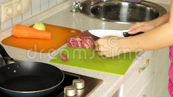 女性手在切割板上切割生肉在厨房准备晚餐视频的预览图