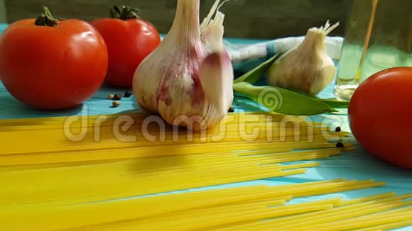 意大利面条油健康食品意大利面一瓶素食慢动作大蒜番茄黑胡椒在蓝色木制背景上视频的预览图