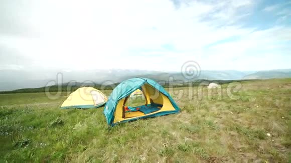 在山上草地之间的营地中的旅游帐篷视频的预览图