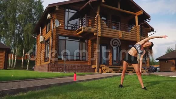 一位身材苗条穿着运动服的漂亮女士正准备在她附近的草坪上开始训练视频的预览图