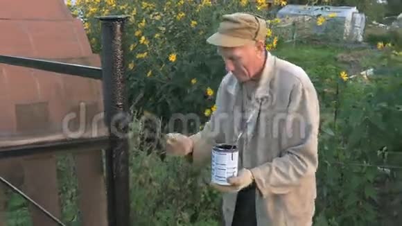 园丁用黑色油漆粉刷铁栅栏视频的预览图