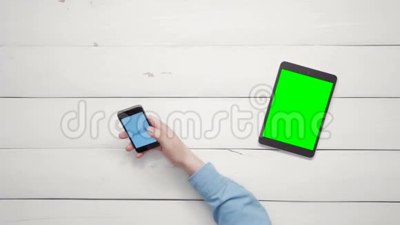 在智能手机和带有绿色屏幕的数字平板电脑上男性双手工作在大数据图表上视频的预览图
