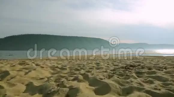 日落时分年轻女子在沙滩上跑来跑去的剪影视频的预览图