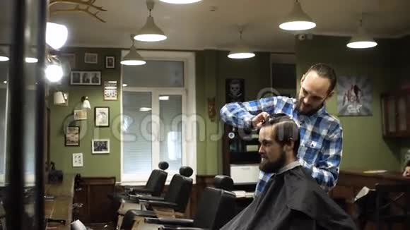 理发师在理发店用剪刀和梳子剪客户的头发视频的预览图