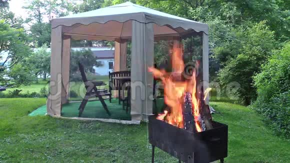 柴禾在花园凉亭和妇女附近的金属烧烤中燃烧视频的预览图