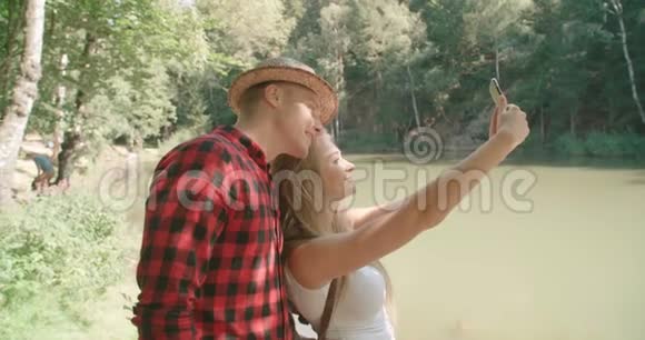 可爱的年轻白种人夫妇在森林里拍摄自我肖像视频的预览图