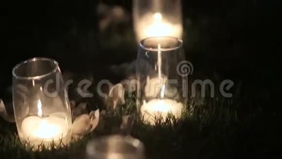 站在草地上的玻璃花瓶里燃烧着浪漫的白色蜡烛视频的预览图