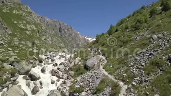 旅行团沿着湍急的河流走在山路上爬山视频的预览图