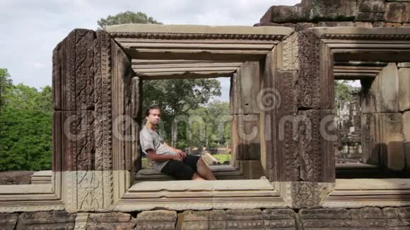 白种人旅游在巴浦翁寺庙看相机吴哥柬埔寨视频的预览图
