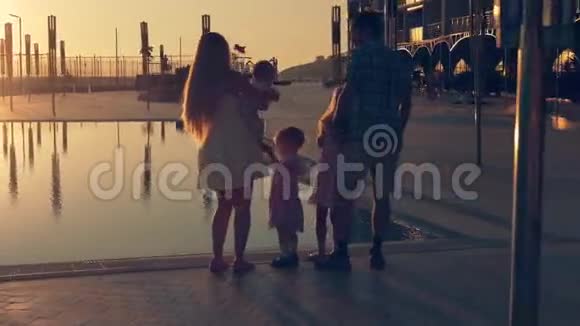 幸福的家庭有三个孩子在欣赏游泳池表面的日落视频的预览图