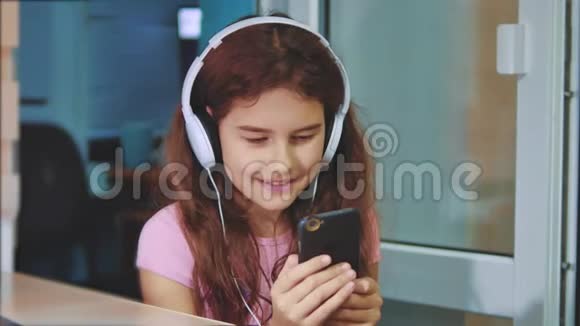 小女孩在智能手机上耳机听音乐青少年女孩在播放列表中的生活方式音乐视频的预览图