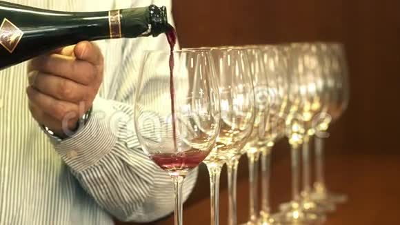 侍酒手将红酒倒入一排水晶酒杯中视频的预览图