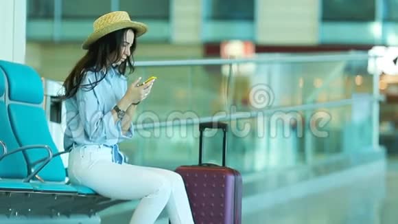 在机场休息室等飞机的年轻女子带智能手机的白人女人在候诊室视频的预览图