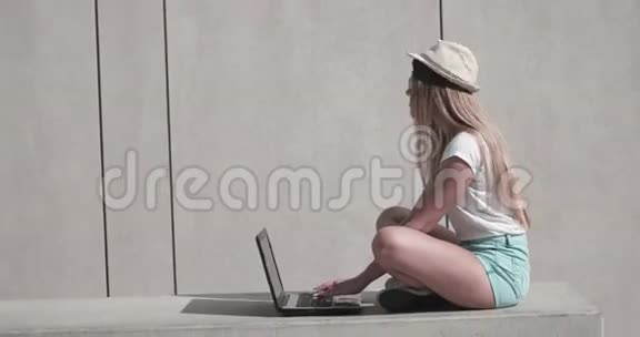 坐在长凳上的学生用她的笔记本电脑视频的预览图