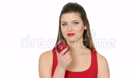 美丽的女孩在白色背景下吃红苹果视频的预览图