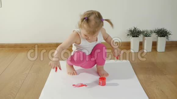 小女孩的双手沾满了红色的颜料手指在地上的一张白纸上视频的预览图