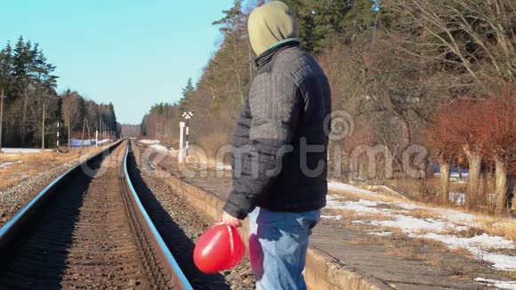 冬天铁路附近有红色心形气球的人视频的预览图
