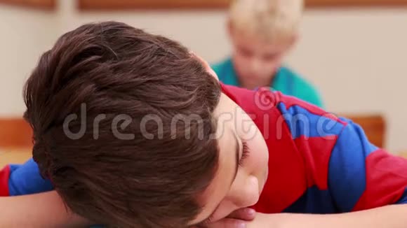 在教室里睡在书上的小男孩视频的预览图