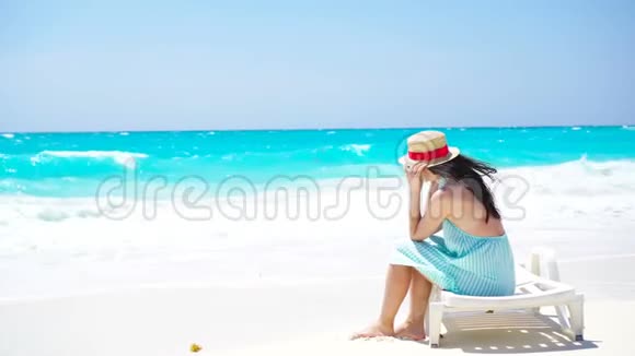 在白沙热带海滩上的年轻美女带帽子的白种人女孩的后景视频的预览图