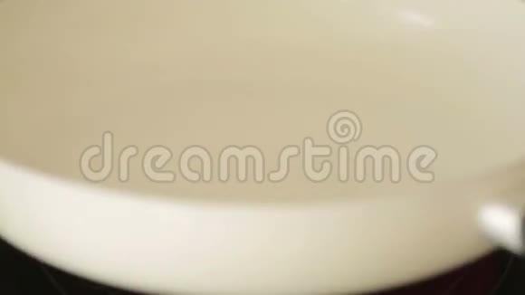女性手把洋葱放进白色的煎锅里视频的预览图